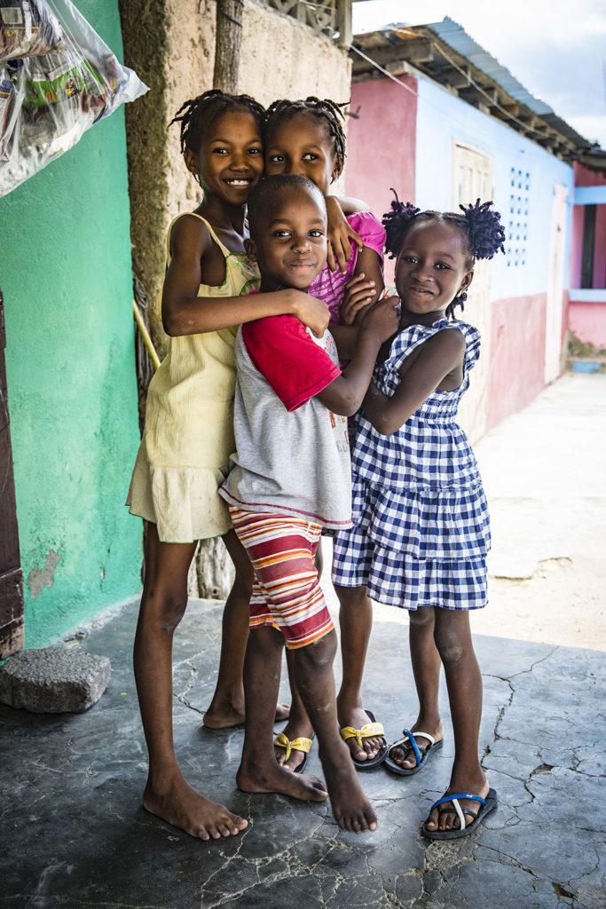 Four children smiling, standing in Haiti.