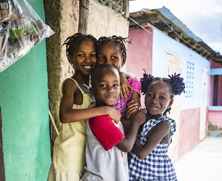 Four children smiling, standing in Haiti.