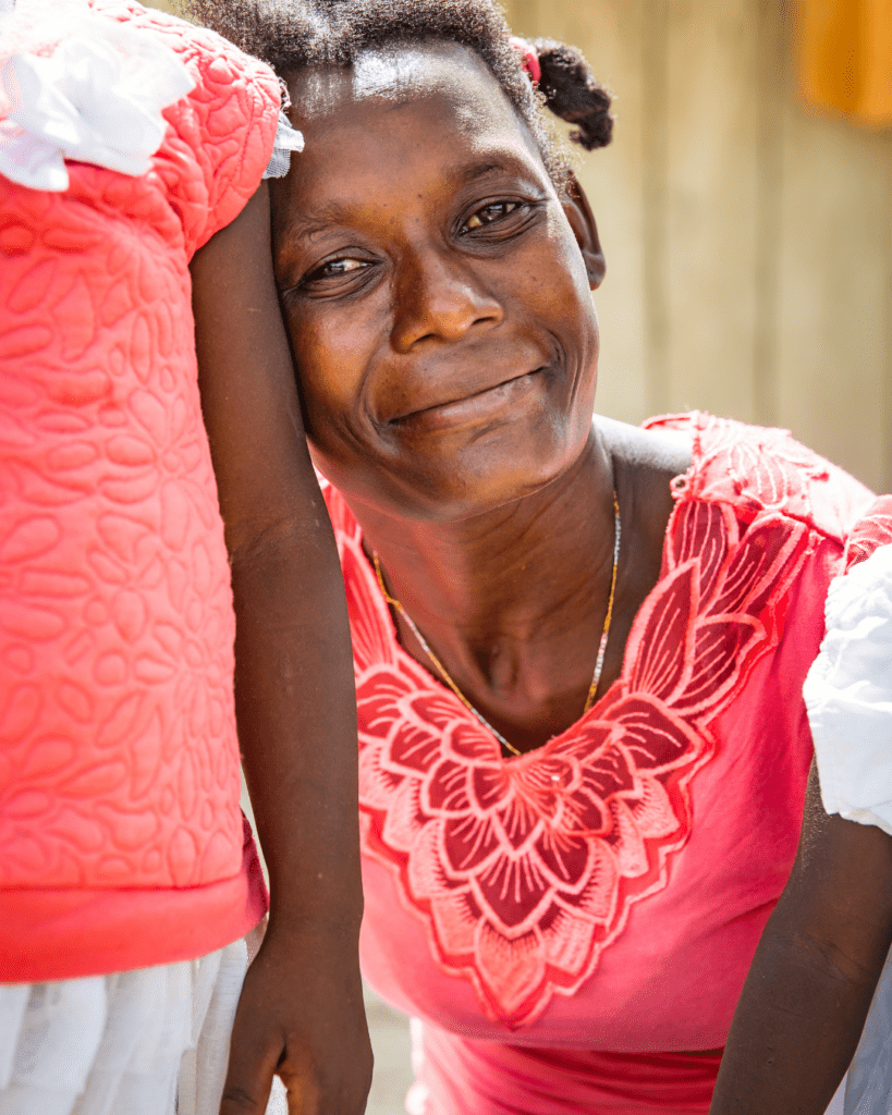 Haitian Woman wearing pink next to daughter.